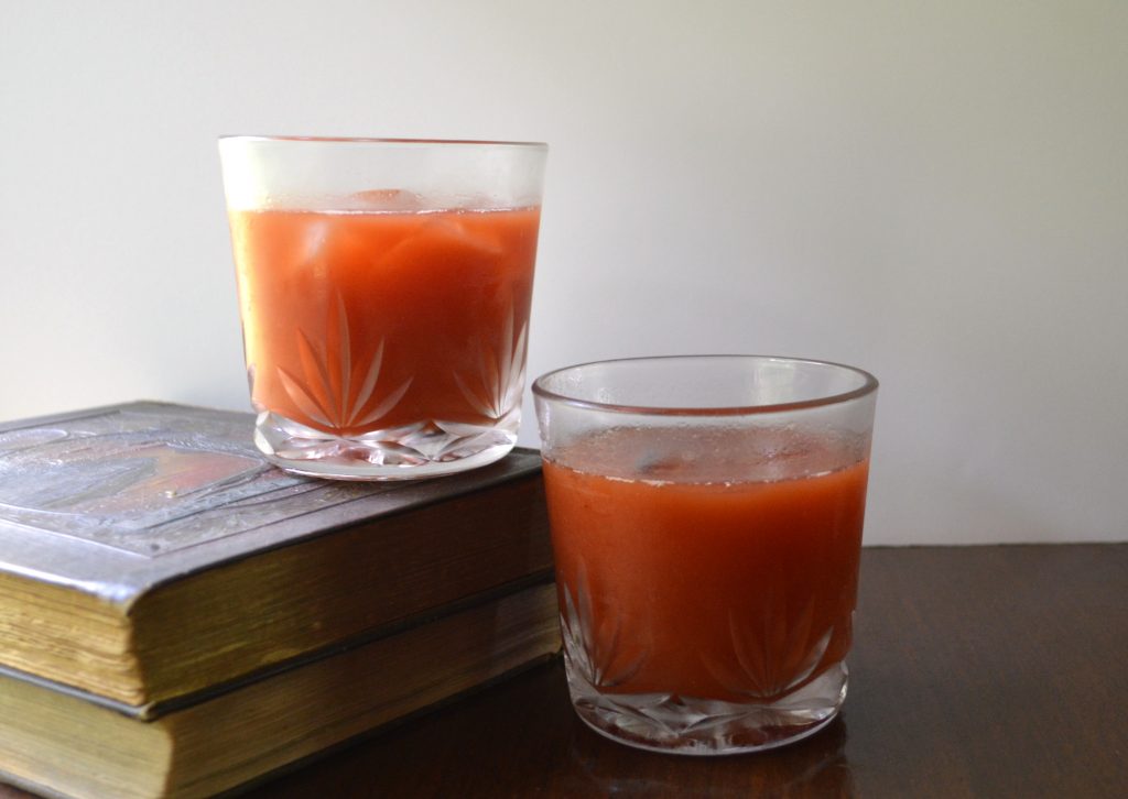 Image of two Bloody Marys in vintage crystal rocks glasses with antique books